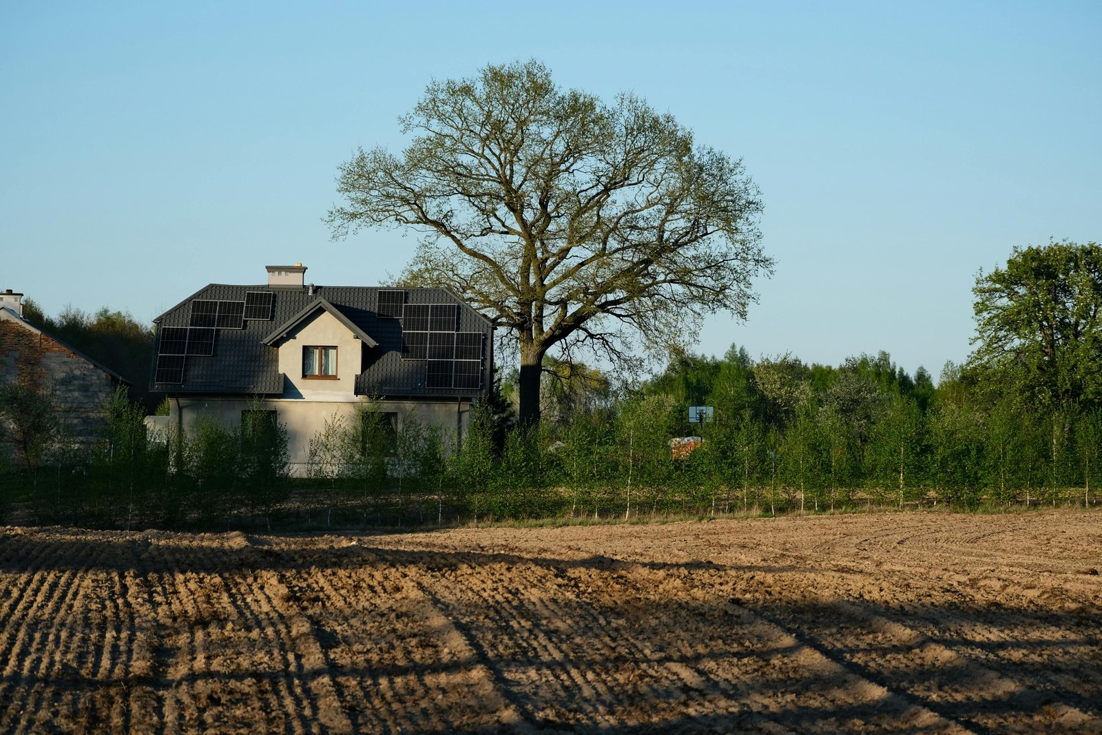 Maison éco-construite entourée de verdure, panneaux solaires sur le toit